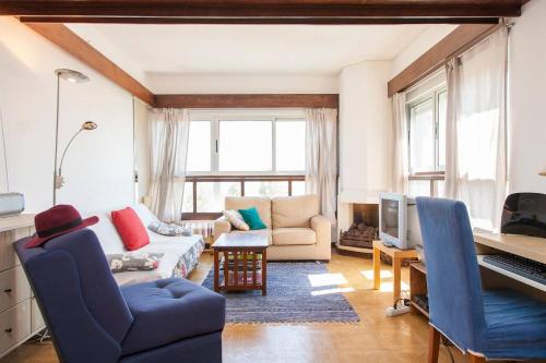 a living room with a couch and a tv at Torres do Mar in São João do Estoril
