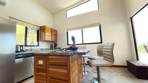a kitchen with a counter and two chairs and windows at Villas Roma Del Mar in Playa Naranjo