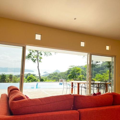a living room with a red couch and a table at Villas Roma Del Mar in Playa Naranjo