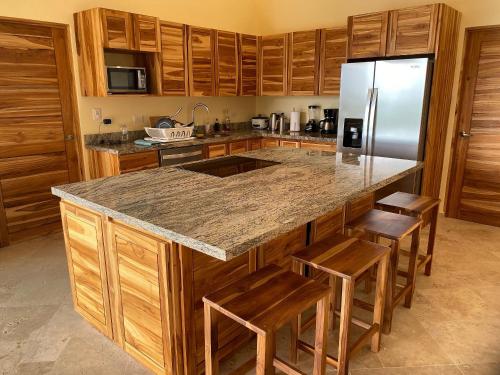 a kitchen with wooden cabinets and a granite counter top at Villas Roma Del Mar in Playa Naranjo