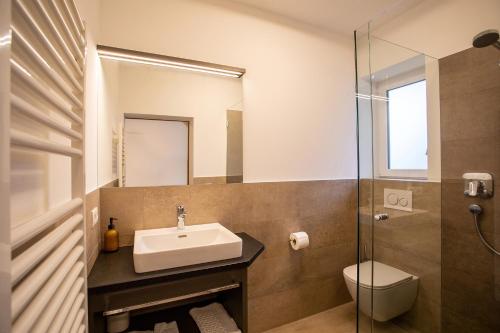 a bathroom with a sink and a toilet and a mirror at Hotel Lamm in Naturno
