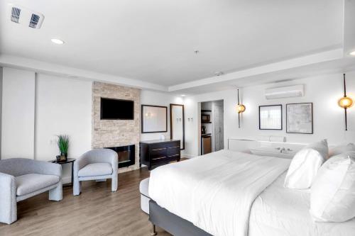 a white bedroom with a large bed and a tv at Hôtel Shediac in Shediac
