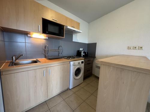 une cuisine avec un évier et une machine à laver dans l'établissement La Pause des 24H - 4pers - WiFi - Rêve au Mans, au Mans