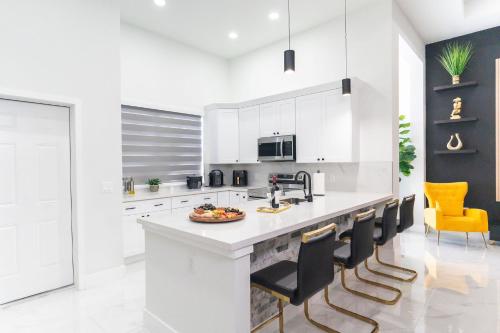 a kitchen with white cabinets and a counter with chairs at Designer Villa with Heated Pool, BBQ, Firepit, Ideal for Families & Groups in Cape Coral
