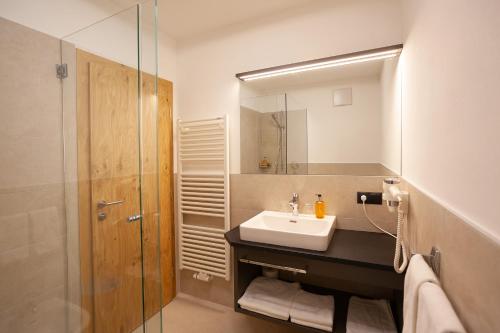a bathroom with a sink and a shower with a mirror at Hotel Lamm in Naturno
