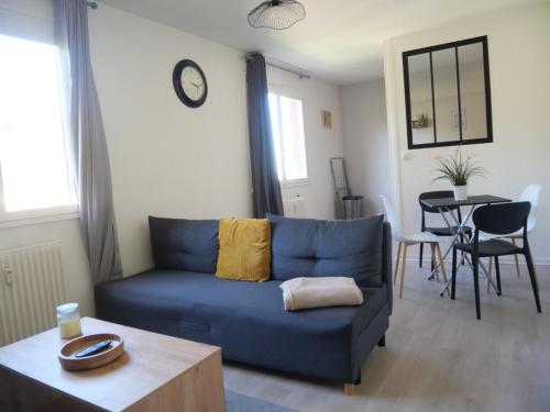 un salon avec un canapé bleu et une table dans l'établissement Les Berceaux Thermal & Parking privé, à Royat