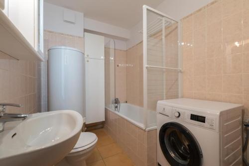 une salle de bain avec une machine à laver et un lavabo dans l'établissement L'Athéna By Tranquil at Home, à Pornichet