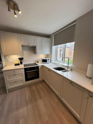 a kitchen with white cabinets and a sink and a window at The CLYDE in Melrose
