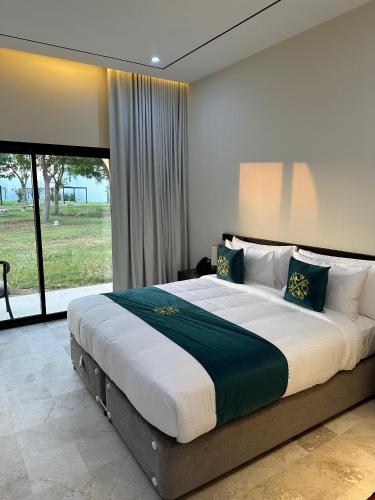 a bedroom with a large bed with a large window at Al Sawadi Beach Resort & Spa in Barka