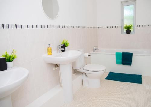 a white bathroom with a sink and a toilet at Lavish 4-Bedrooms with Modern Home Features - Sleeps 8 - Hi-Speed Wi-Fi - Luxury Garden - Private Ample Parking in Peterborough