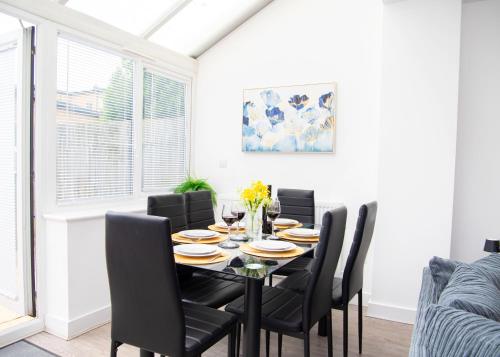 a dining room with a black table and chairs at Lavish 4-Bedrooms with Modern Home Features - Sleeps 8 - Hi-Speed Wi-Fi - Luxury Garden - Private Ample Parking in Peterborough
