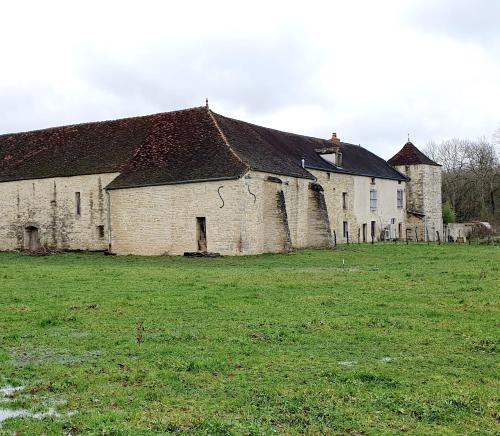 an old stone building in a field with a grass yard at La Grande Vesvre in Gigny