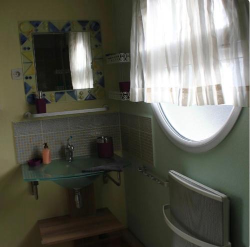 une salle de bain avec un lavabo et une fenêtre dans l'établissement gîte Joséphine, à Attin