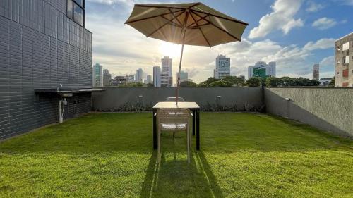 a chair with an umbrella on top of a lawn at TOLIVE One Housi Recife by Carpediem in Recife
