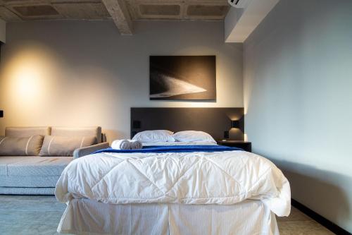 a bedroom with a white bed and a couch at TOLIVE One Housi Recife by Carpediem in Recife