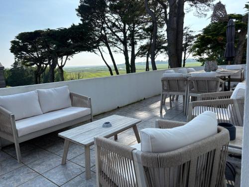 d'une terrasse avec des canapés, des tables et des chaises. dans l'établissement Villa Vieilles Vignes vue mer, à Billiers