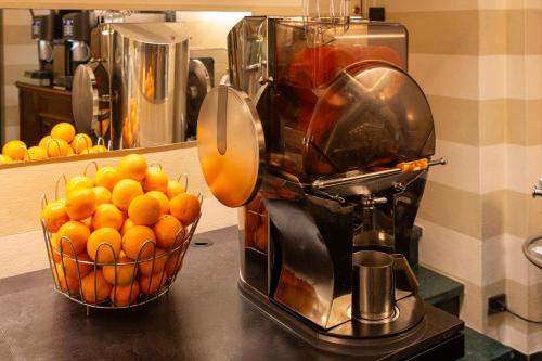 a juicer sitting on a counter with a basket of oranges at Hotel Ancora in Verbania