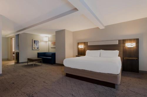 a hotel room with a bed and a blue chair at Holiday Inn Express Hotel & Suites - The Villages by IHG in The Villages