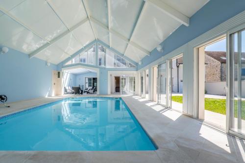 une piscine intérieure dans une maison avec des fenêtres dans l'établissement Disneyland Paris Maison de prestige, à Villeneuve-le-Comte