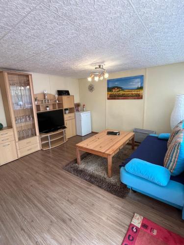 a living room with a blue couch and a table at Bungalowdorf Briesensee in Neu Zauche