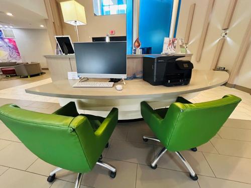 a table with a computer and two green chairs at Holiday Inn Express & Suites Shippensburg by IHG in Shippensburg