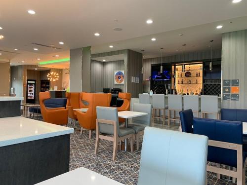 a restaurant with white tables and orange chairs at La Quinta by Wyndham Opelika Auburn in Opelika