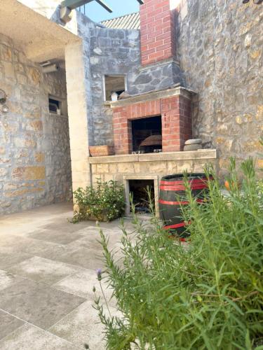 a brick fireplace in a stone building with plants at Visilo Heritage Stone House - A 300-year-old Legacy in the Heart of Pučišća in Pučišća