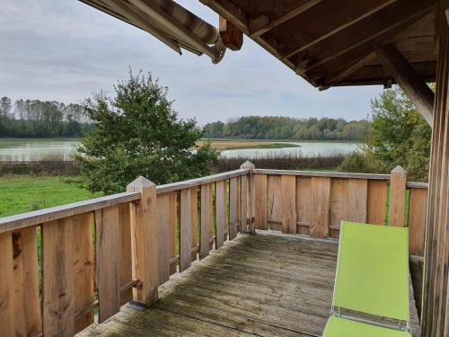 a wooden deck with a green chair on it at La Fuste des Garceaux in Orconte