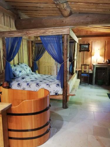 a bedroom with a bed with blue curtains at La Fuste des Garceaux in Orconte