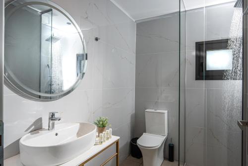 a bathroom with a sink and a toilet and a mirror at Georgia's Garden by Omilos Hotels in Amoudara Herakliou