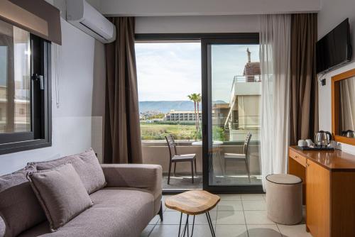 a living room with a couch and a kitchen with a view at Georgia's Garden by Omilos Hotels in Amoudara Herakliou