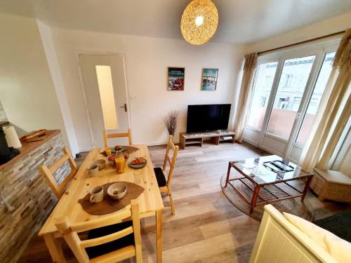 un salon avec une table en bois et une télévision dans l'établissement La Corderie - Centre Ville - Parking, à Saint-Brieuc
