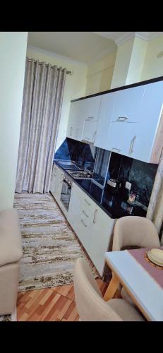 a kitchen with white cabinets and a table and chairs at White Luxury Villa Apartments &Hot Tab in Durrës