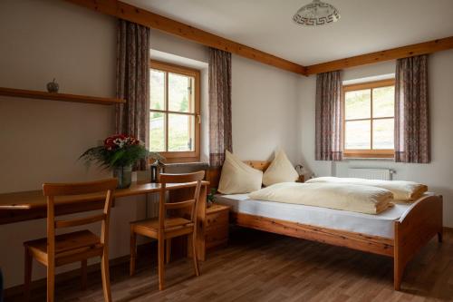 a bedroom with a bed and a desk and two chairs at Kirchsteigeralm in Hafling