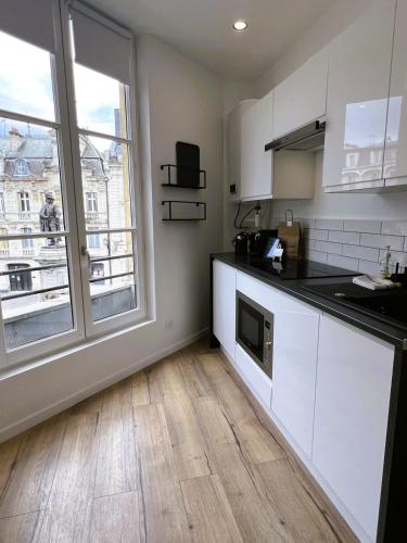 une cuisine avec des placards blancs et une grande fenêtre dans l'établissement Suite Isabelle - 2 pers Le charme intemporel, à Charleville-Mézières