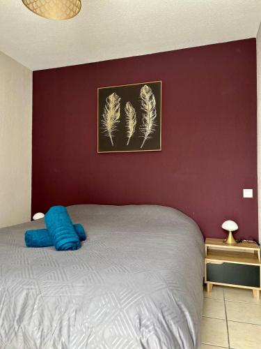 une chambre avec un lit et un mur rouge dans l'établissement Le Vallon Appartement T2, à Trébas