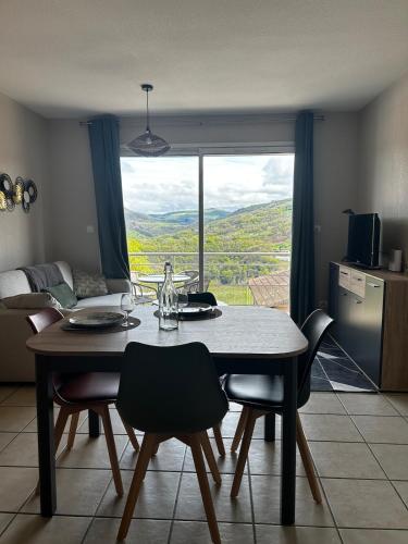 une salle à manger avec une table et des chaises et une fenêtre dans l'établissement Le Vallon Appartement T2, à Trébas