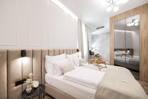 a bedroom with a large white bed and a mirror at De Pusterla Luxury Rooms in Zadar
