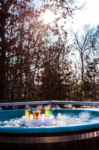 a hot tub with four glasses of beer in it at Atostogų namas su baseinu, jacuzzi ir pirtimi in Klaipėda