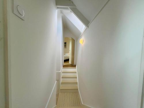 a hallway with white walls and stairs with a skylight at La maison de l'Orangerie - Charm & comfort in the very heart of Carentan in Carentan