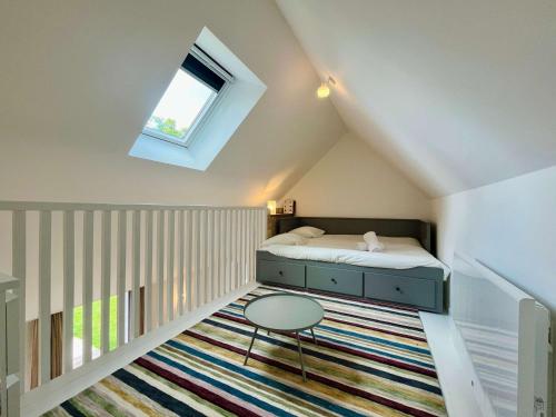 a small attic bedroom with a bed and a table at La maison de l'Orangerie - Charm & comfort in the very heart of Carentan in Carentan