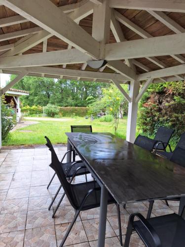une table et des chaises noires sous un toit en bois dans l'établissement Les Hauts Benquey, à Mérignas