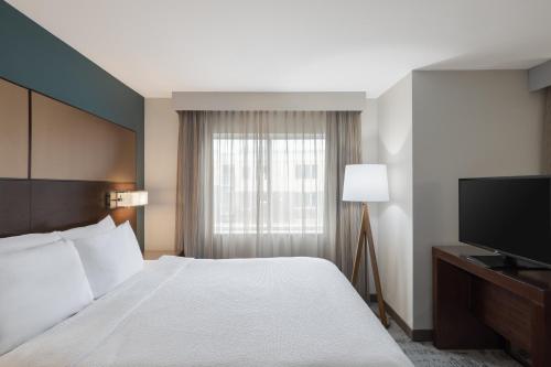 a hotel room with a bed and a flat screen tv at Residence Inn by Marriott Des Moines Downtown in Des Moines