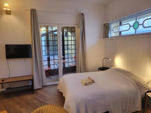 une chambre avec un lit blanc et une fenêtre dans l'établissement Le Patio St Jacques, à Perpignan