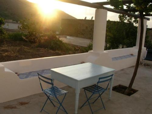 a white table and two blue chairs on a patio at Villa I Geki in Malfa