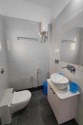 a white bathroom with a toilet and a sink at V & U Homestay Sadar in Nagpur