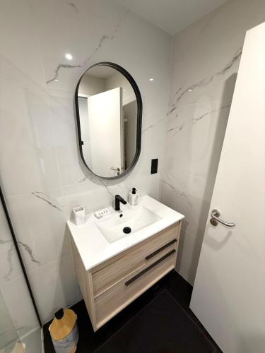 a white bathroom with a sink and a mirror at Appartement standing calme in Rodez