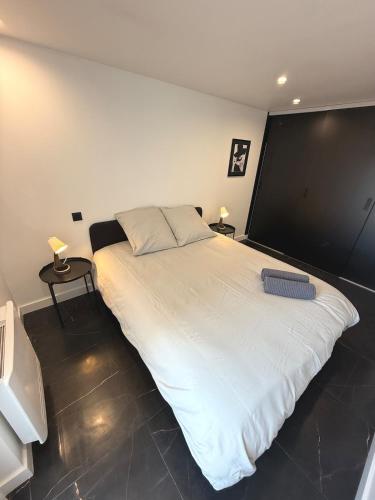 a large white bed in a room with two tables at Appartement standing calme in Rodez