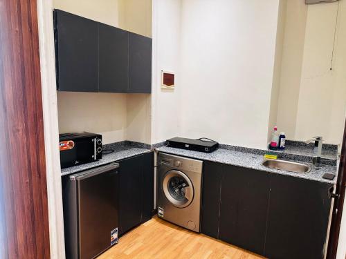 a small kitchen with a washing machine and a sink at Urban Garden Retreat Cozy Studio and Private Patio in Cairo