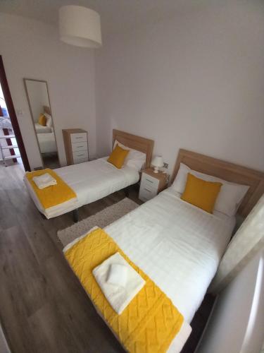 two beds in a room with yellow pillows at Home from home in Noya